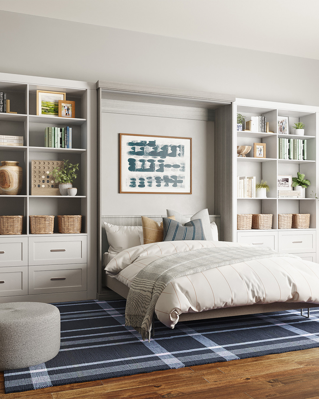 A modern bedroom featuring a neatly made Murphy bed, built-in shelves with books and baskets, a blue plaid rug, and framed abstract art above the headboard—perfect for those seeking stylish Murphy bed ideas.