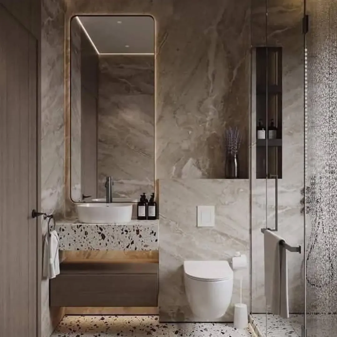 Modern bathroom with marble walls, a large mirror above a floating sink, and a wall-mounted toilet showcases stylish small bathroom decor. Glass shower and neatly arranged toiletries complete this elegant take on half bathroom ideas.