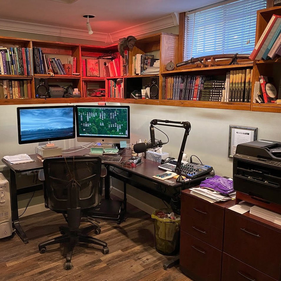 Home Office Workshop setup featuring dual monitors, a microphone, audio mixer, printer, and shelves filled with books surrounding a corner desk—perfect for inspiring new workshop ideas.