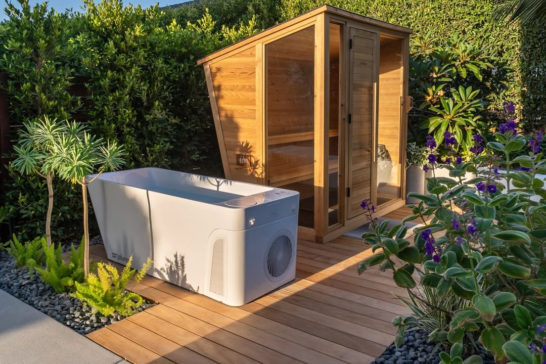 A modern outdoor setup featuring a white cold plunge tub and a wooden sauna on a wooden deck, surrounded by lush greenery—perfect for those seeking gorgeous outdoor saunas and fresh outdoor sauna ideas.