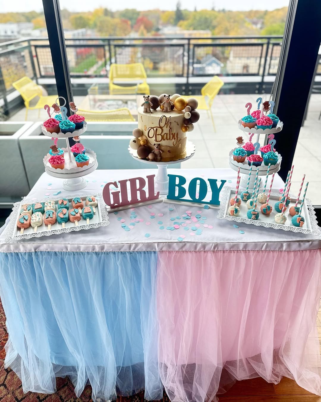 A decorated gender reveal party dessert table with pretty desserts in pink and blue, a cake reading