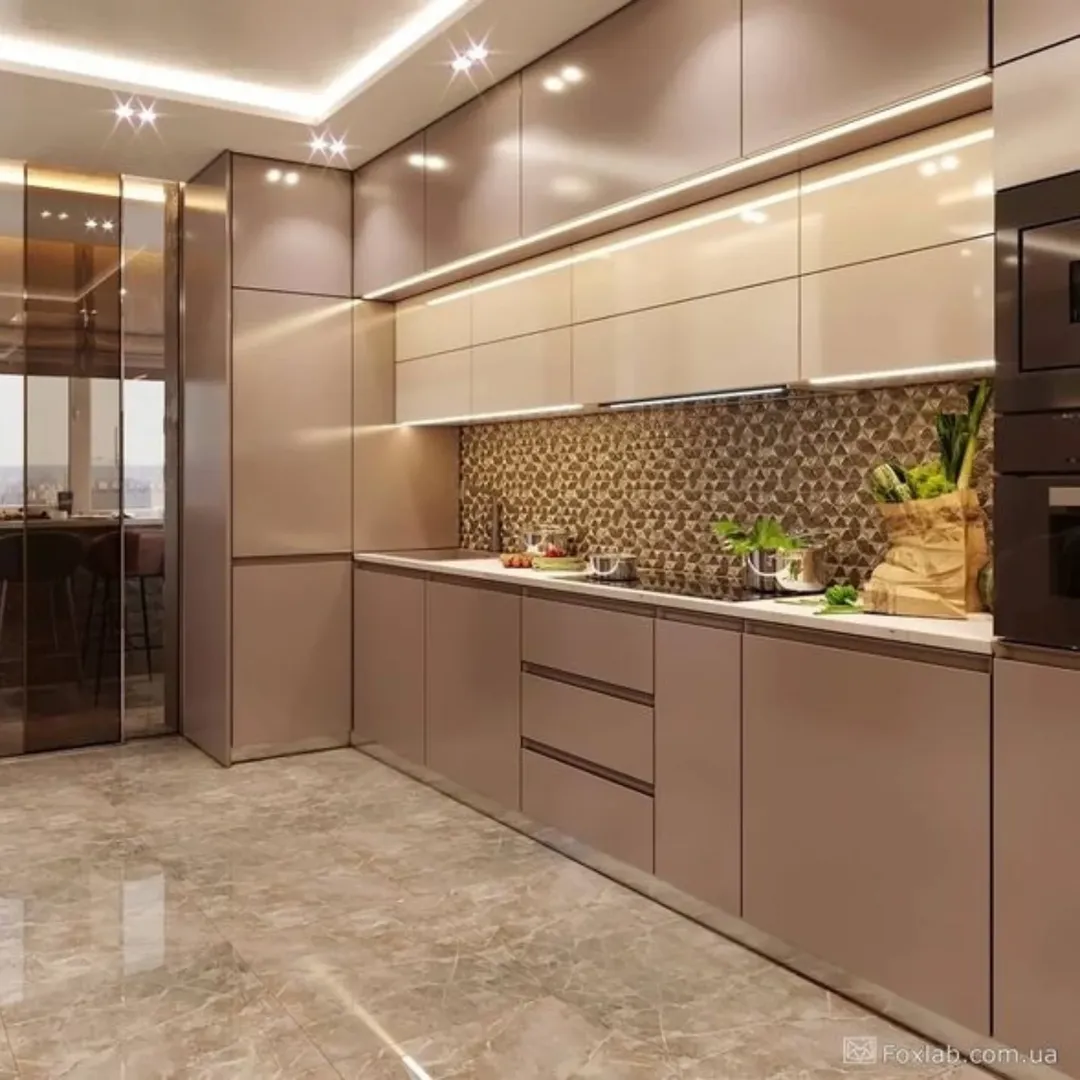 Modern kitchen with beige cabinets, a patterned backsplash, under-cabinet lighting, and a marble floor. Showcasing kitchen design trends and stunning kitchen colors for 2025, cooking utensils and fresh vegetables sit on the countertop.