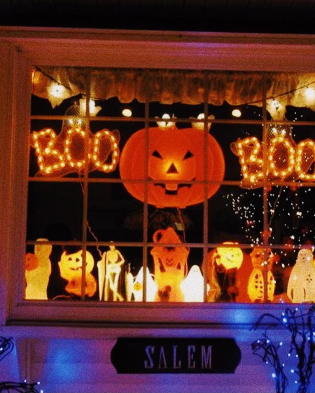 A window adorned with glowing Halloween lights spelling "BOO," featuring a large jack-o