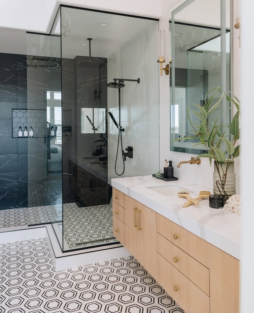 Modern bathroom with light wood cabinetry, white countertop, hexagonal patterned floor tiles, large mirror, and a glass-enclosed shower with black fixtures—perfect inspiration for spa-worthy bathroom design.
