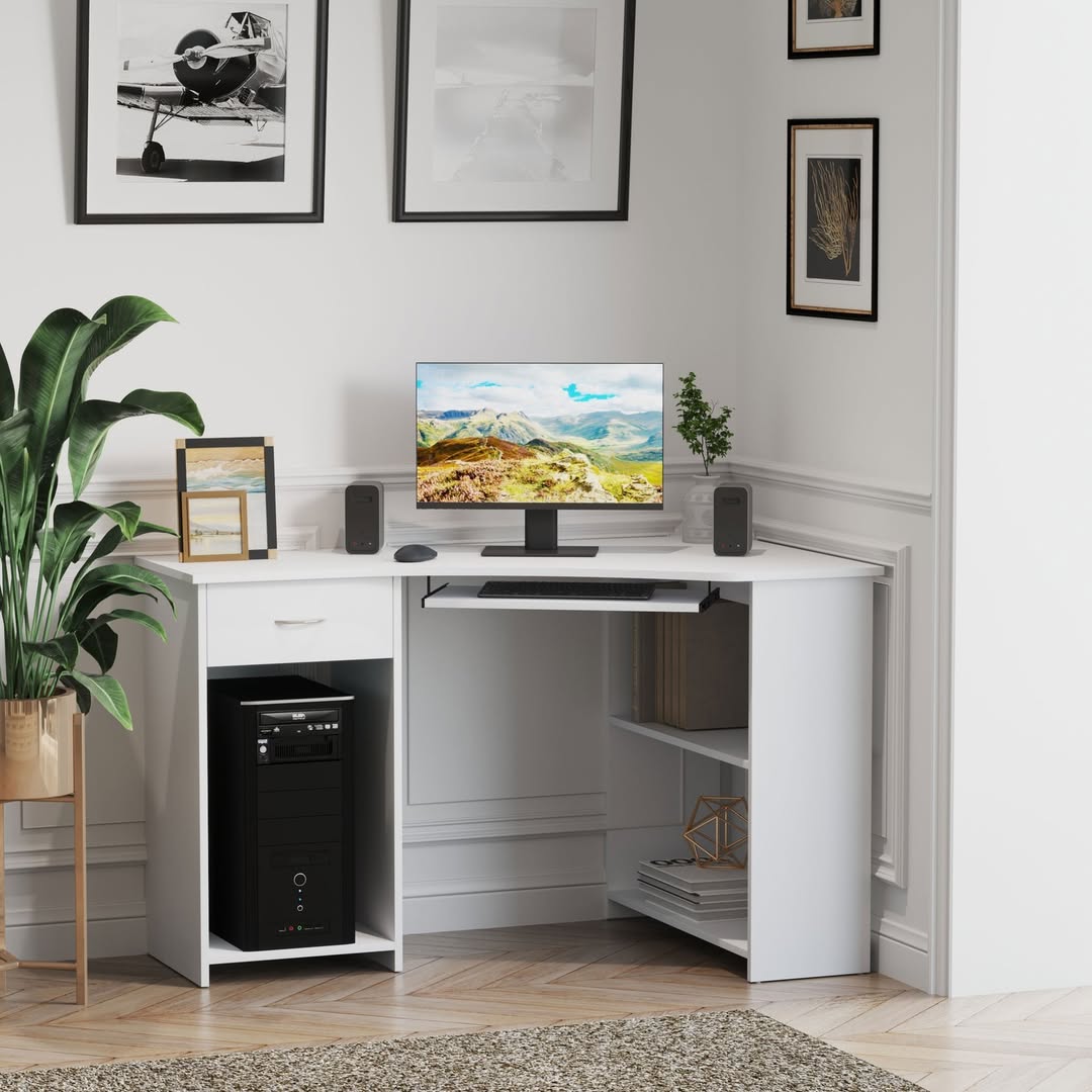 A modern home office corner showcases sleek computer desk design with a white desk, desktop computer, speakers, keyboard, framed art, and a potted plant on a herringbone wood floor.