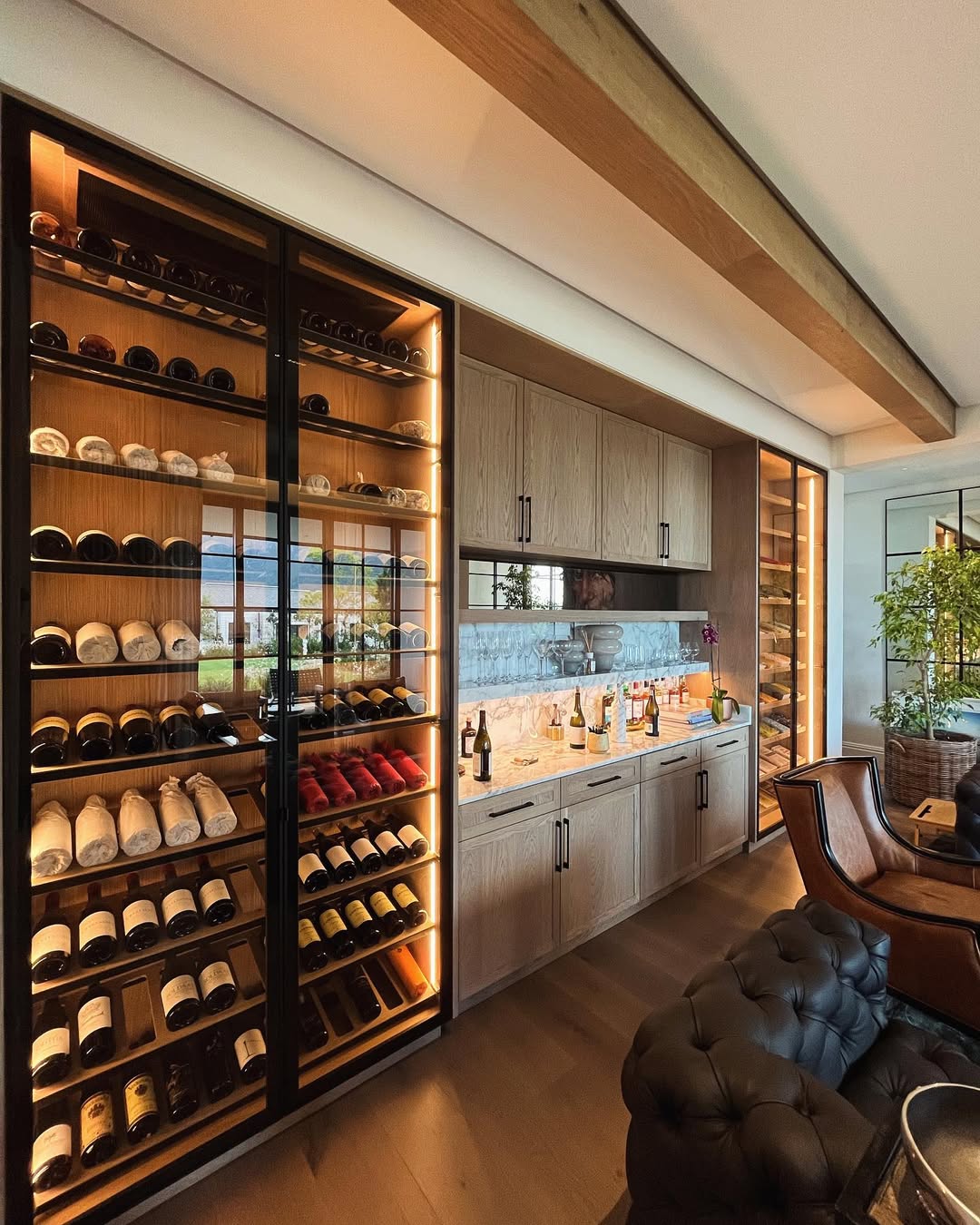 Modern home wine bar with floor-to-ceiling wine racks, a sleek countertop, glass cabinets, and under-cabinet lighting—perfect for showcasing your favorite wine storage ideas in a contemporary living space.