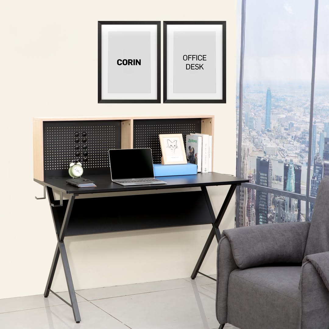 A modern black computer desk with shelves holds a laptop, clock, plant, and books—perfect for those seeking fresh desk ideas. Two framed prints above read