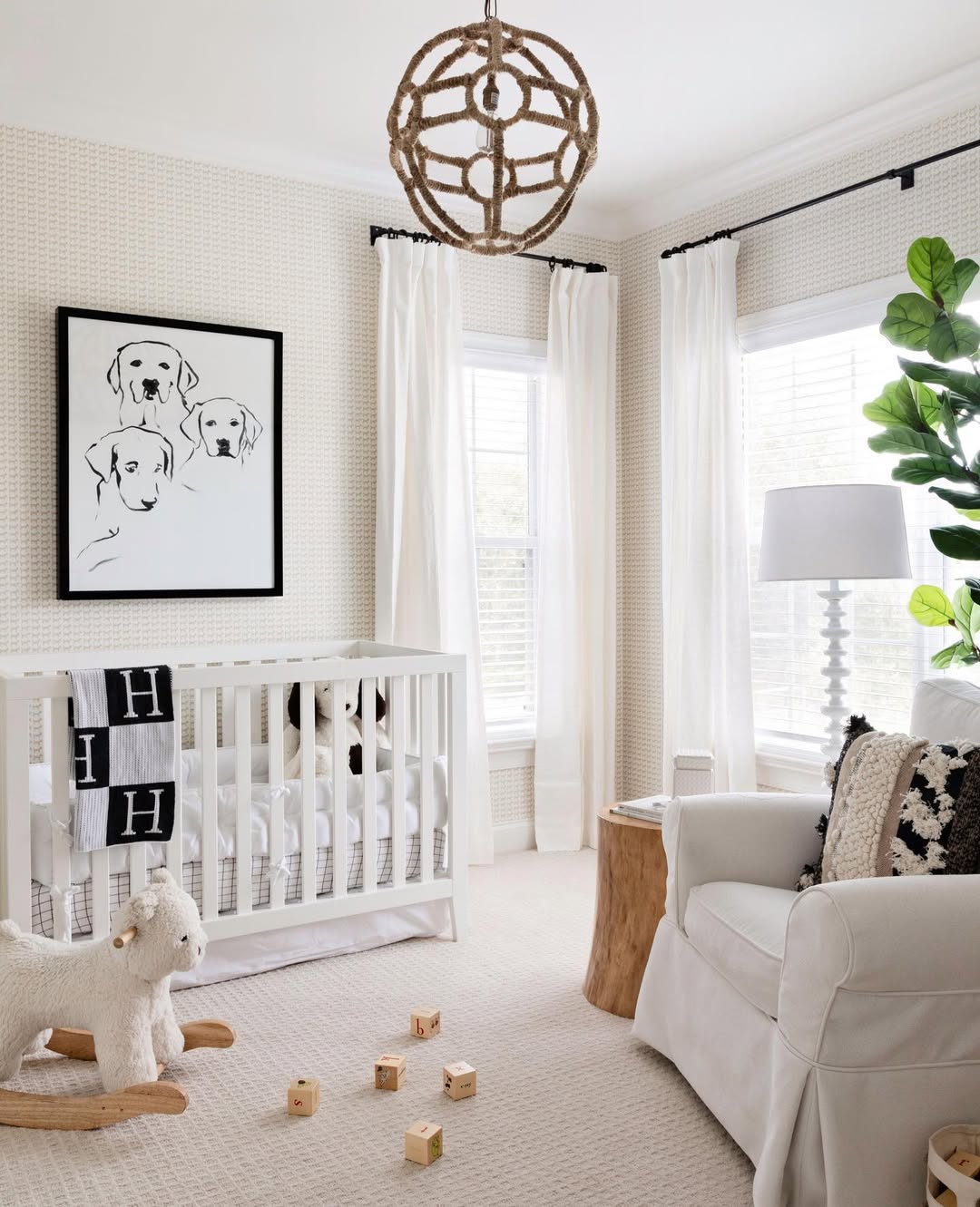 Bright nursery with a white crib, armchair, plush sheep rocker, wooden blocks, and a framed dog illustration. Perfect inspiration for first-time moms seeking baby boy nursery ideas in 2025. Sunlight pours in through two windows and a large plant adds a fresh touch.