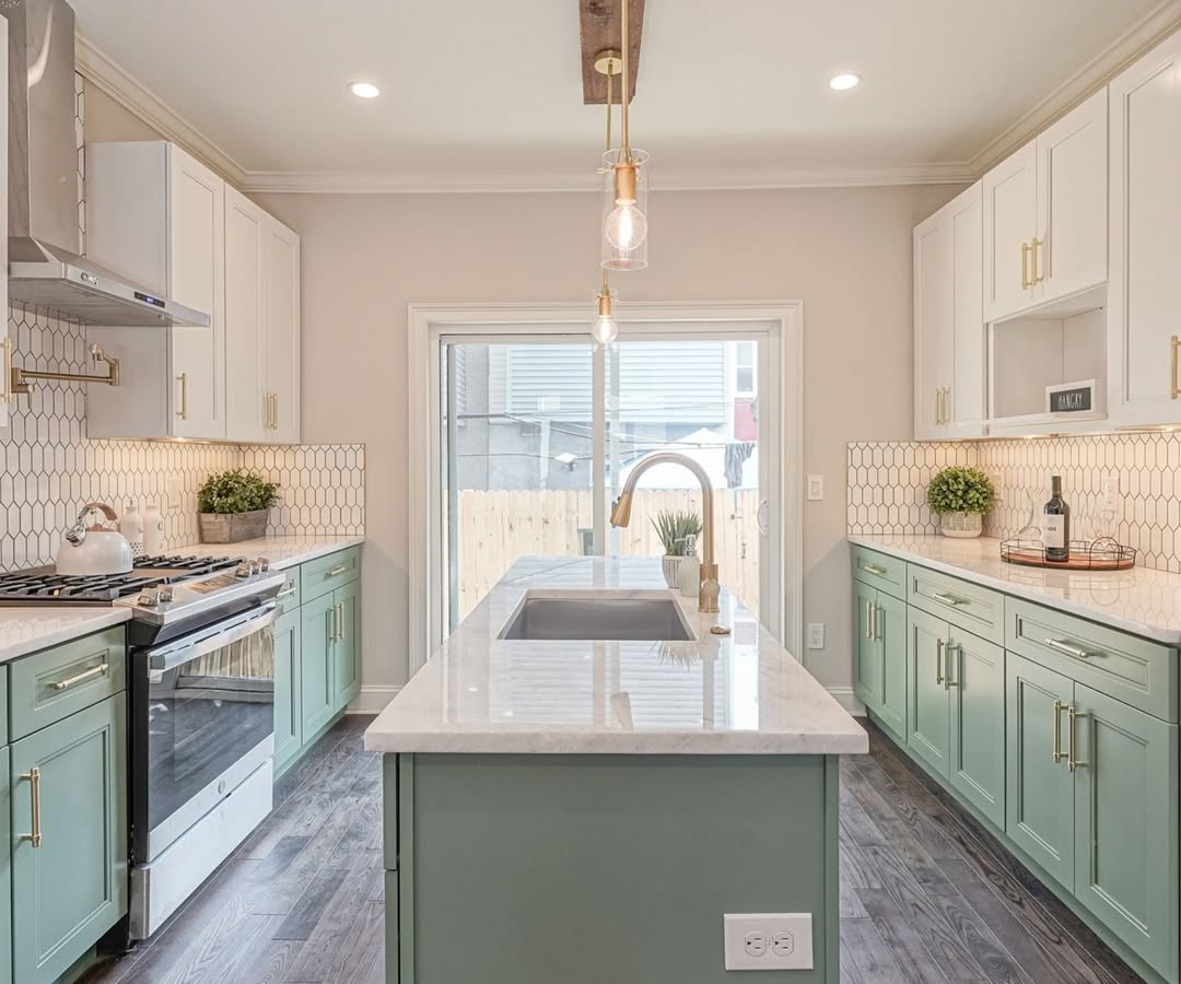 Modern kitchen with green lower cabinets, white uppers, marble countertops, a central island with sink, stainless steel appliances, and geometric tile backsplash—perfect inspiration for stunning kitchen colors and fresh kitchen color ideas.