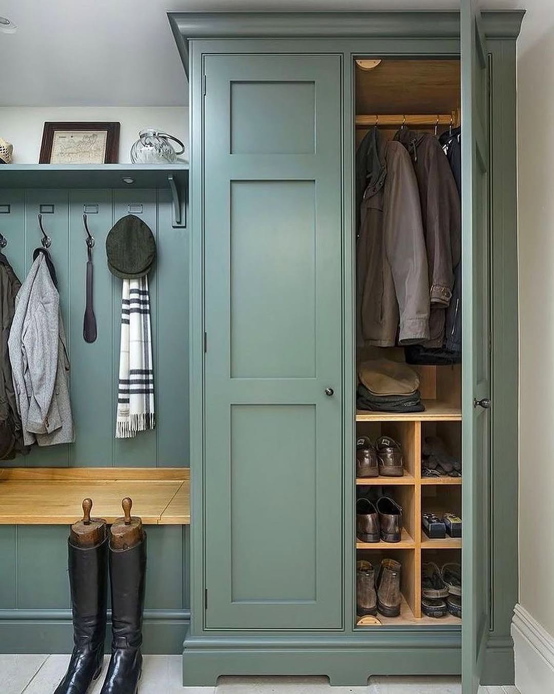 A green built-in mudroom unit with a coat rack, bench, boots, and a cabinet offers smart home organization, keeping jackets and neatly organized shoes on wooden shelves.