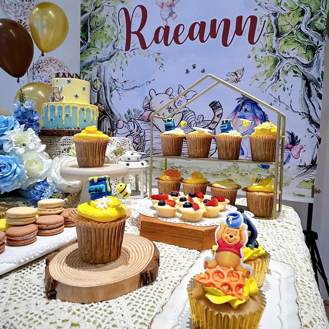 A dessert table featuring cupcakes, macarons, and tarts decorated with a Winnie the Pooh theme, perfect for party desserts at a celebration with a