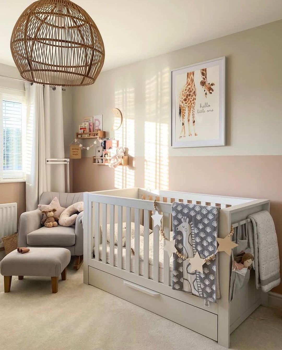 A chic baby boy nursery features a white crib, gray armchair with ottoman, stuffed animals, rattan light fixture, and giraffe-themed wall art—perfect inspiration for baby boy nursery ideas in 2025.