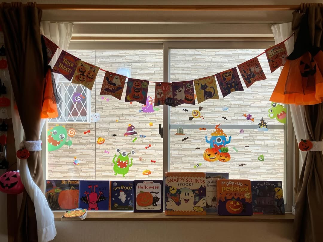 A window decorated with Halloween-themed garlands, stickers, and pumpkins highlights creative Halloween window decoration ideas; children
