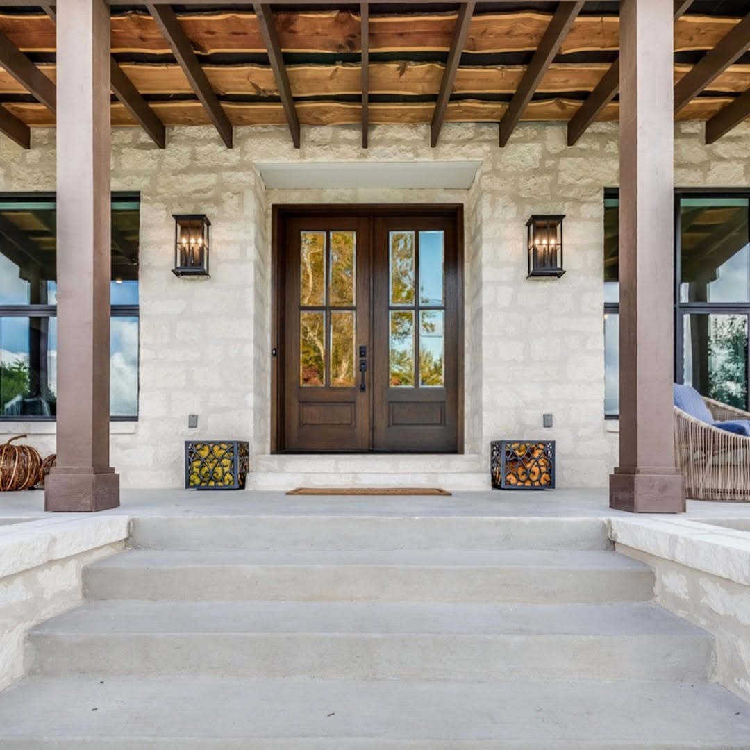 Front porch with stone steps, a stunning double door entryway, two lantern-style lights, decorative boxes, and a wooden pergola overhead—perfect for inspiring new entryway ideas.