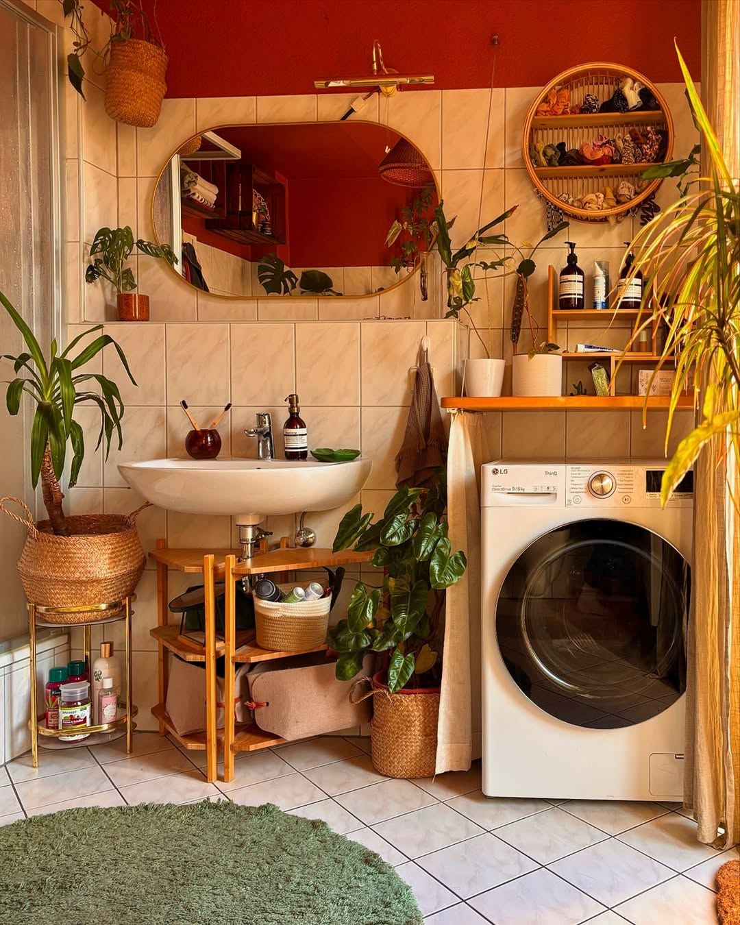 A cozy Boho laundry room with a washing machine, sink, mirror, potted plants, woven baskets, wooden shelves, and sunlight streaming through a window—perfect inspiration for boho laundry decor.