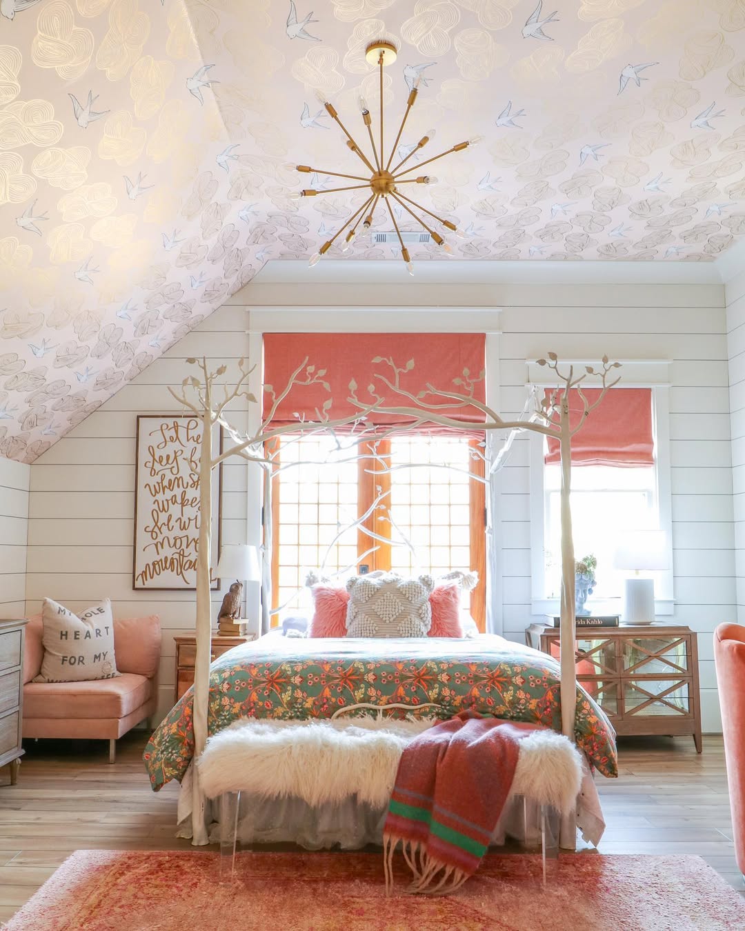 A bright bedroom with a canopy bed, fur throw, patterned bedding, coral accents, and bird-and-leaf wallpaper on the sloped ceiling—perfect for women bedroom ideas and fresh bedroom inspiration.